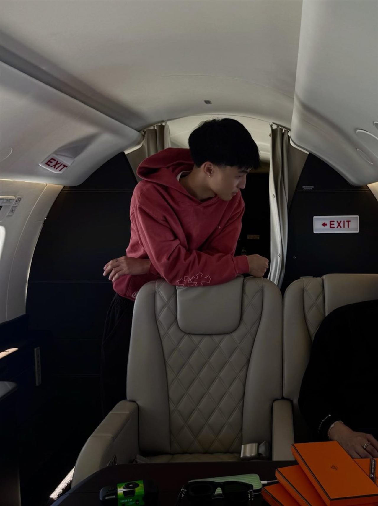 Clayton Kim in a red hoodie, leaning into the cabin of a private jet